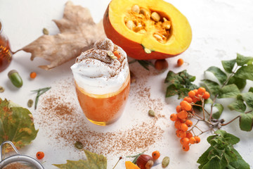 Composition with tasty pumpkin coffee on white background