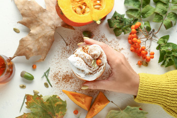 Female hand with glass of tasty pumpkin coffee on white background
