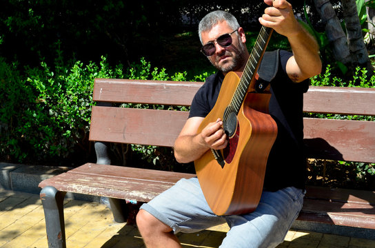 Man setting in the park playing the guitar
