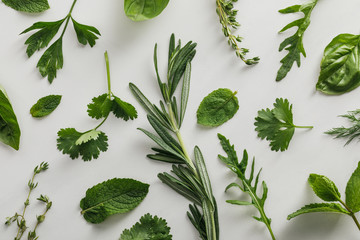 Top view of arugula, basil, cilantro, dill, parsley, rosemary and thyme sprigs on white background - obrazy, fototapety, plakaty
