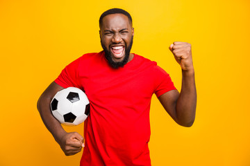 Photo of soccer team trendy african black funny captain wearing red t-shirt holding soccer ball prepared to win local cup while isolated with yellow background - Powered by Adobe