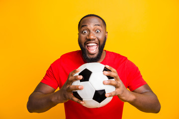 Photo of cute childish rejoicing american man ready to play football while isolated with yellow background