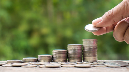 The hands of investors holding coins placed on gold coins at a level different from financial...