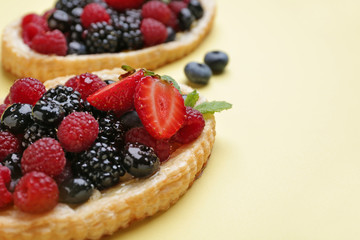 Sweet tartlet with berries on color background