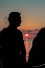 the concept of tourism, recreation-a happy man overlooking the sea and the sunset. silhouette of the people