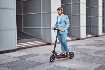 Miggle aged broker in protective helmet is driving his new electro scooter to the work.