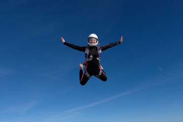 Fototapeta na wymiar Skydiving. Blonde girl is flying in the blue sky.