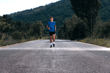 Fototapeta premium Male athlete running on an empty road in the woods while trying to get to the red finish line.