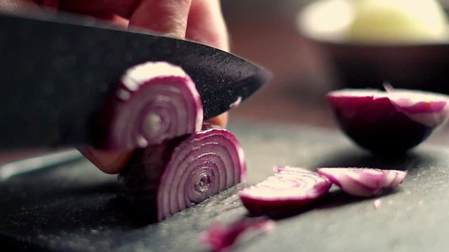 Closeup of male hands cutting onion on the board, slow motion