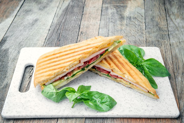 Healthy Grilled Basil mozzarella Caprese Panini Sandwich white Board on wooden table. Classic Italian fast food