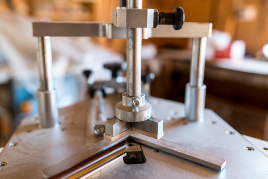 Underpinner on focus, picture framer tool in a small workshop, shallow depth of field.