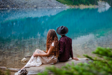 Fototapeta premium couple sitting on log and looking at lake