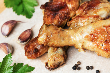 Roasted chicken legs with spices and herbs on a light background .