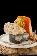 Delicatessen spicy cheeses of different varieties. Red cheddar, Dor blue, Stilton, Belper Knoll on beautiful textured wooden background. Spicy appetizer for gourmets. Selective focus.