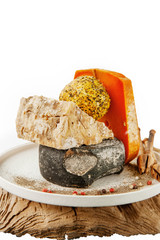 Delicatessen spicy cheeses of different varieties. Red cheddar, Dor blue, Stilton, Belper Noll on beautiful textured wooden background. Spicy appetizer for gourmets. Selective focus.Isolated on white