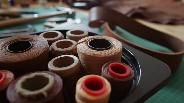 Close up of set of brown thread spools standing in box in leather workshop