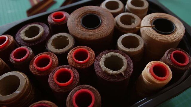 Close up of brown thread spools standing in box in leather workshop
