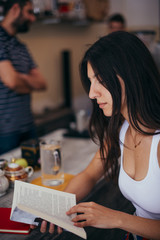 Girl at the cafe drinking a hot drink and reading a book