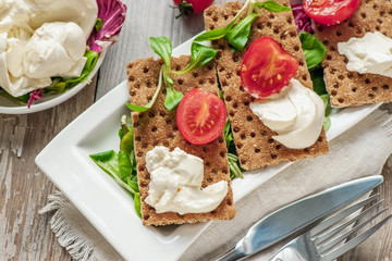 Burato cheese and salad on diet bread. Lollo Rosso lettuce, cress salad and other green herbs. The concept of a healthy diet for the weight loss . Italian dish. Selective focus