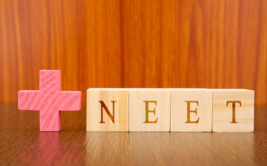 NEET a medical Exam conducted at India in wooden block leters on table.
