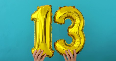 Gold foil number 13 thirteen celebration balloon on a blue background - Powered by Adobe