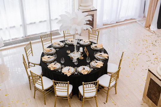 Top view on the luxurious round wedding table for guests. The table with black tablecloth and stylish details.