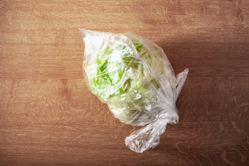 iceberg lettuce vegetable in plastic bag. single use plastic packaging issue