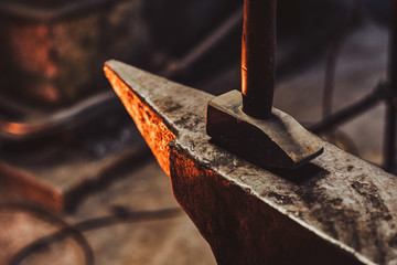 Close up photo shoot of hammer and anvil at dark smith workshop.