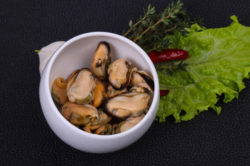 Pickled mussels in the bowl served pepper, garlic and salad