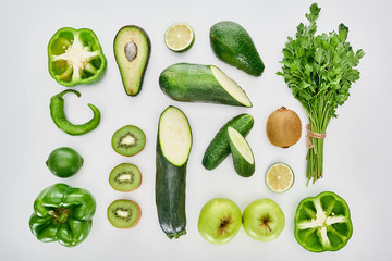 top view of apples, avocados, cucumbers, limes, peppers, kiwi, greenery and zucchini