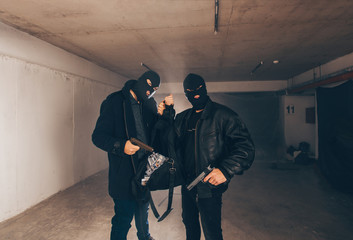 Satisfied thiefs holding guns and money in sack