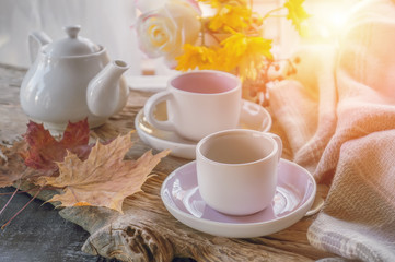 Naklejka na ściany i meble beautiful autumn composition with tea. autumn leaves and cups with grape sugar on a rustic tree background. the concept of the fall season. soft selective focus