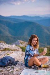 Naklejka na ściany i meble Young lady taking selfie with her phone while marveling the view from the top of the world at sunset. Success, winner, zen, tranquility.