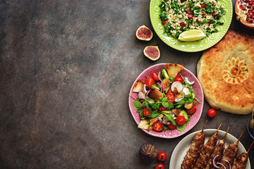 Arabic and Middle Eastern dinner table, meat kebab,tabbouleh salad, Fattoush salad,pita on a dark rustic background. Top view, flat lay, copy space