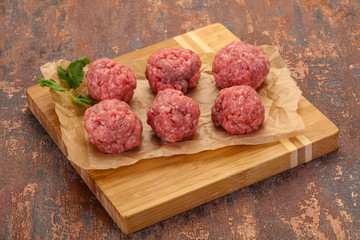 Raw meatball over wooden background