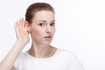 Young woman with hand at her ear is listening