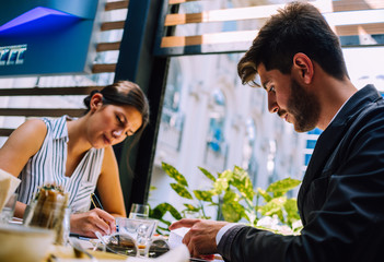 Couple of young serious business people sitting in a coffee bar