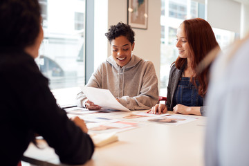 Team Of Young Businesswomen In Meeting Around Table In Modern Workspace