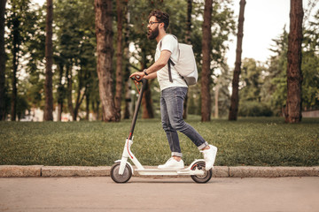 Modern citizen traveling by eco electric scooter on sidewalk
