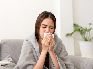 Asian young woman is sick, unwell, cold and have a flu symptoms on the sofa.