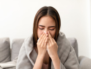 Asian young woman is sick, unwell, cold and have a flu symptoms on the sofa.