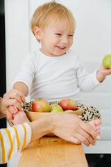 Fototapeta premium lly blond toddler boy is explores, plays with apples from backet.