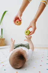 Little boy is lying on the diaper, and play with apples