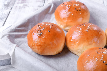 Yeast buns with sesame seeds on an oven tray