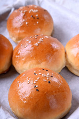 Yeast buns with sesame seeds on an oven tray