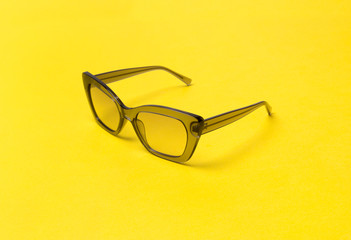 Gray modern fashionable sunglasses on yellow background.