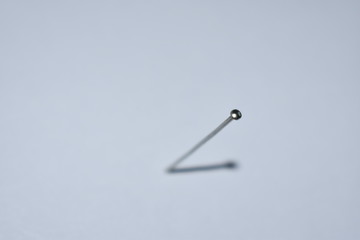 A nail on a light background with its shadow depicts a clock hand