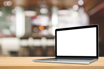 Blank white screen laptop computer on wood table top with cafe restaurant abstract bokeh light defocused blur background