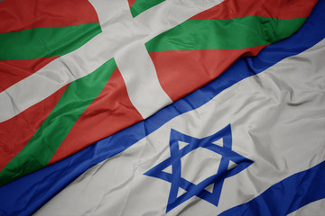 waving colorful flag of israel and national flag of basque country.