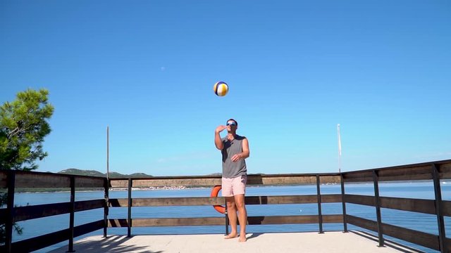 A man hitting a volleyball towards the camera in slowmotion